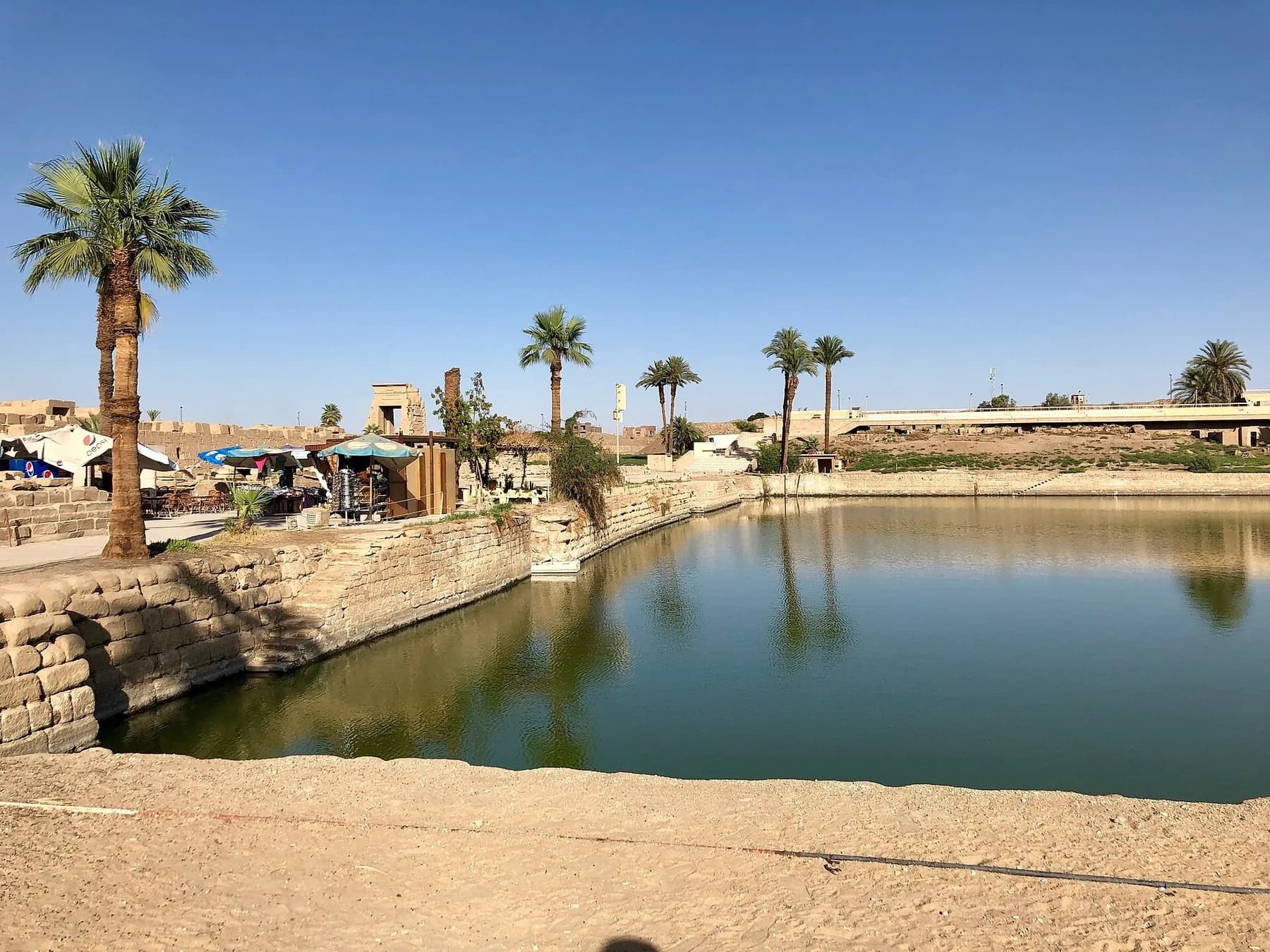 The Sacred Lake with palms and stone embankment on a clear day