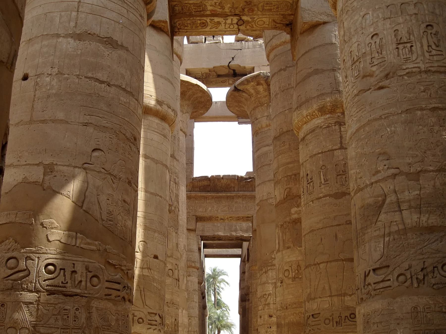 Massive papyrus columns of the Great Hypostyle Hall with carved reliefs, view along an aisle