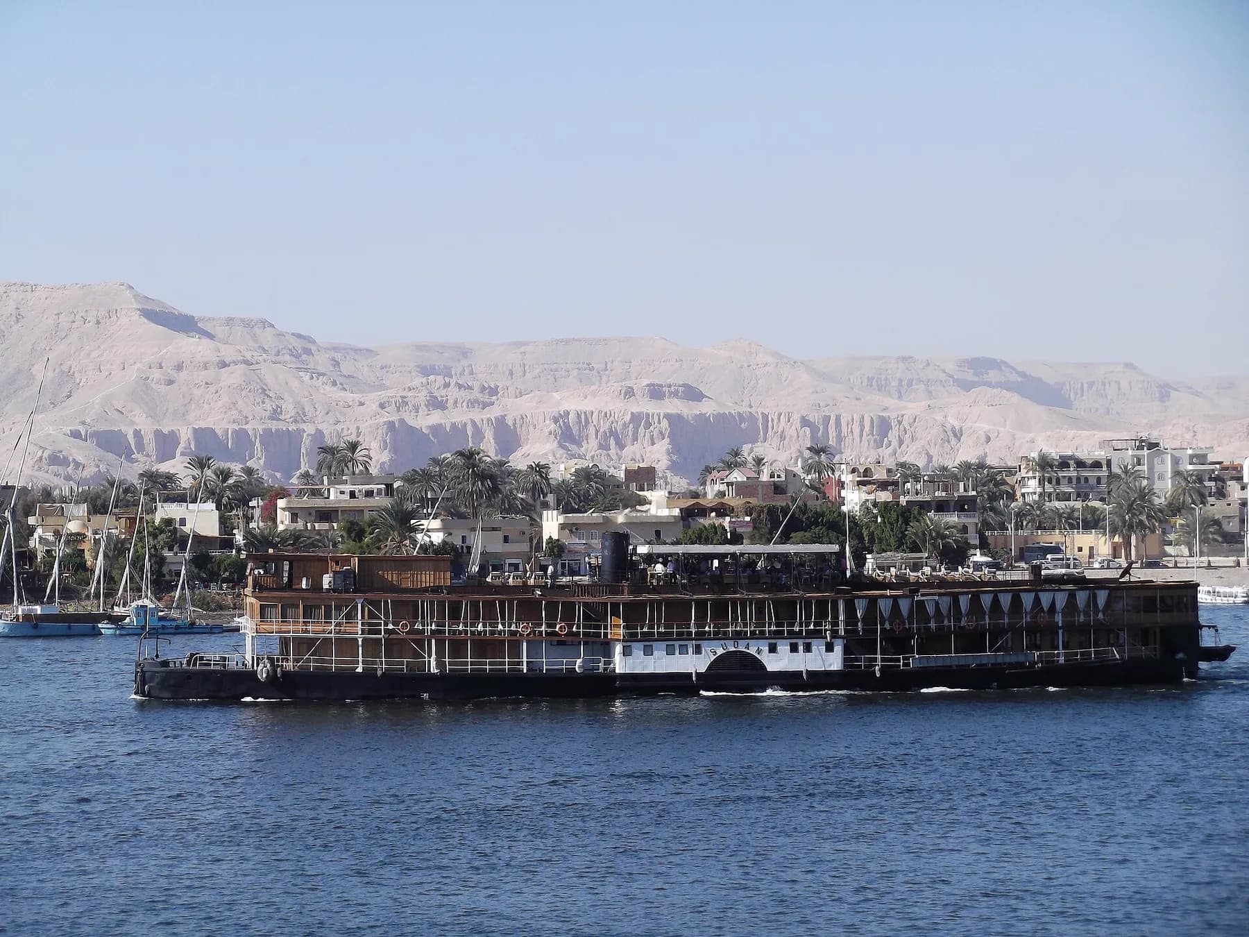 Historic paddle steamer Sudan under way, Theban hills behind
