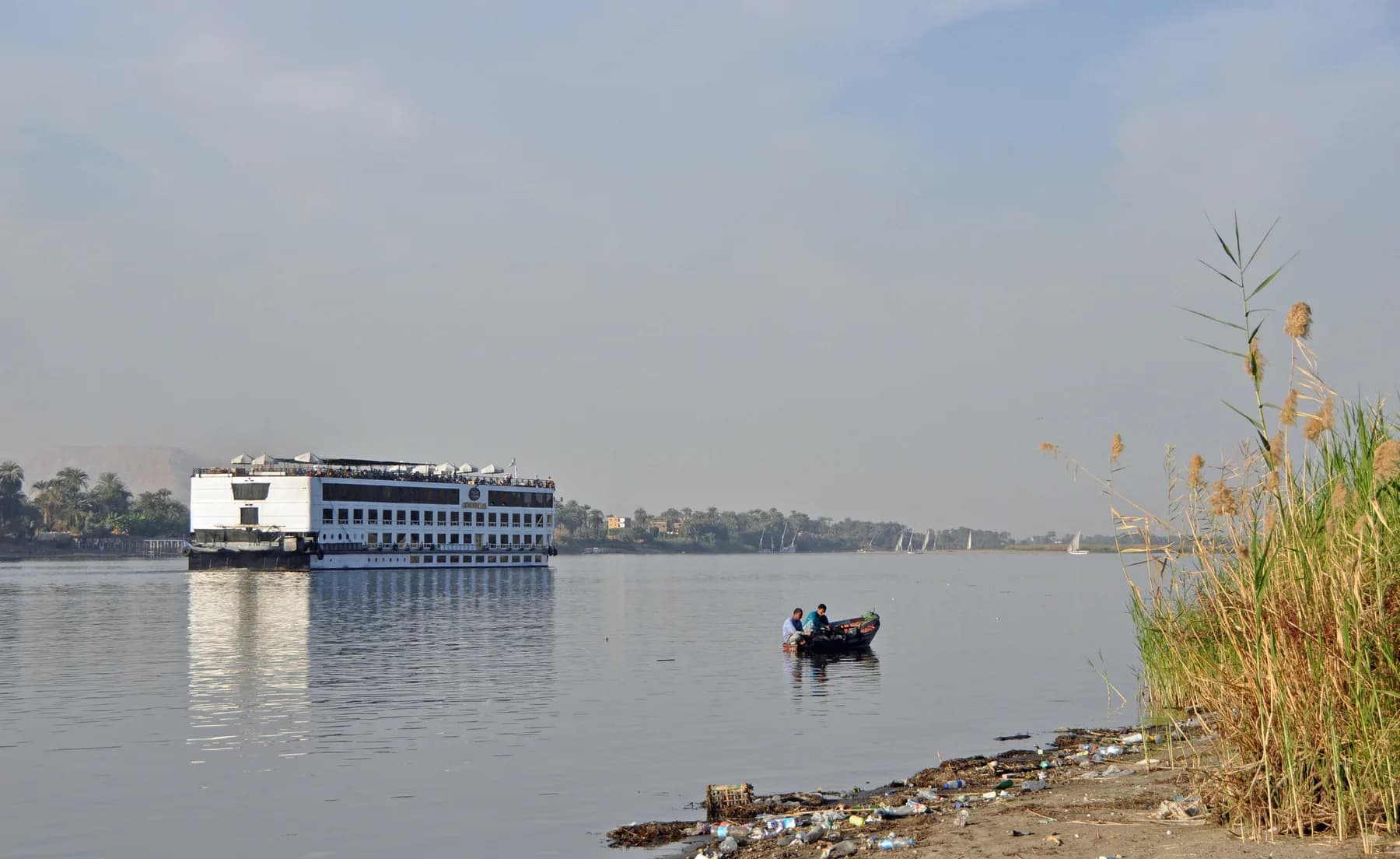 Hazy winter morning on the Nile south of Luxor, cruise ship and small boat