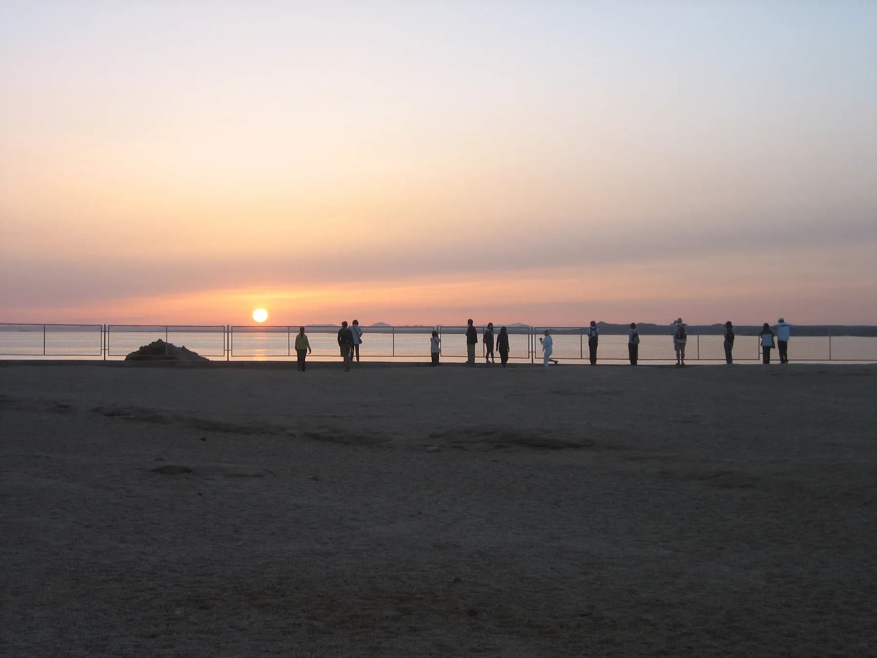 Visitors silhouetted along Lake Nasser shore watching sunrise at Abu Simbel