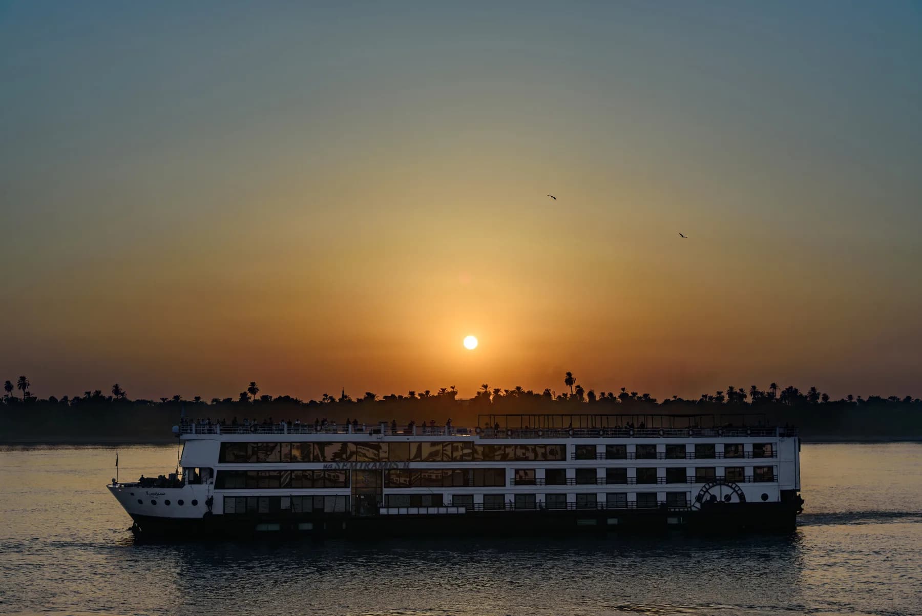 Cruise ship M/S Semiramis II silhouetted on the Nile at sunset