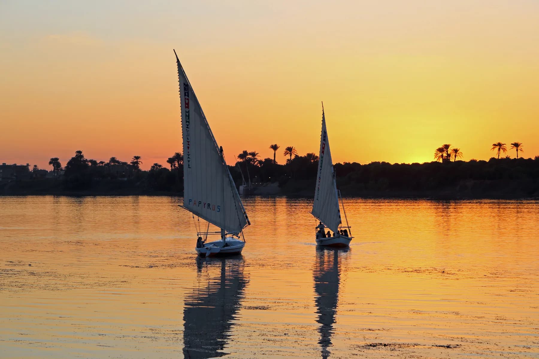 Two feluccas backlit at sunset on the Nile, Luxor