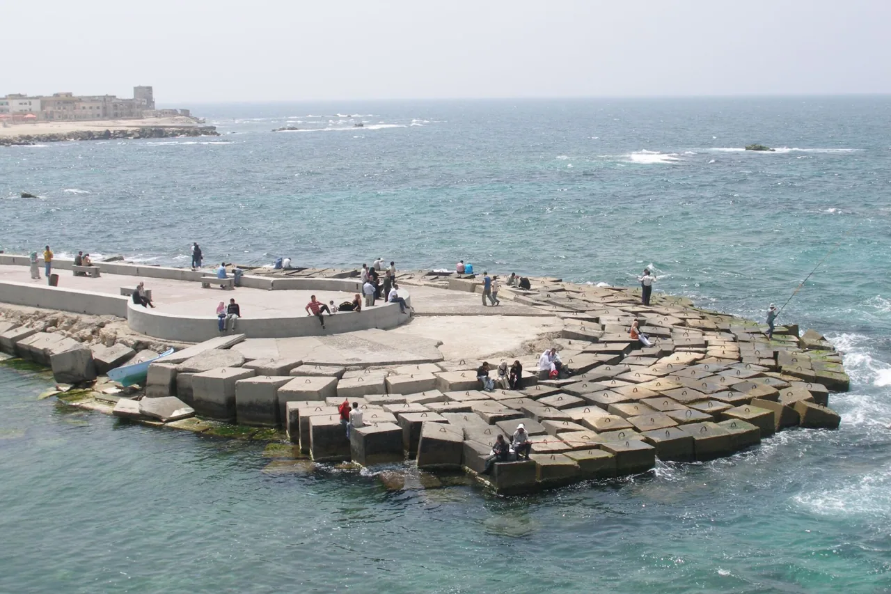 Alexandrians fishing with rods from a concrete breakwater on the Mediterranean seafront