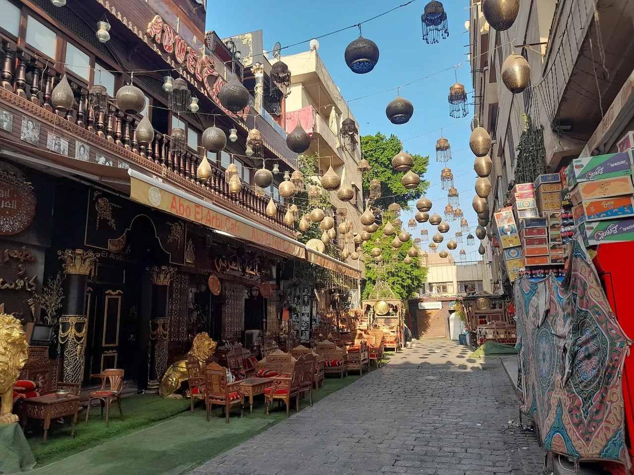 Café seating and brass lanterns in a lane of historic Cairo